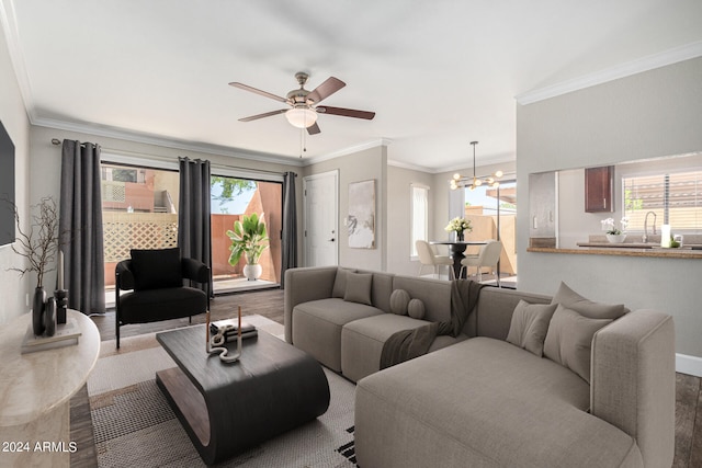 living room featuring ceiling fan with notable chandelier, crown molding, and a healthy amount of sunlight