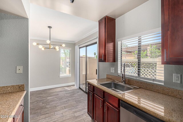 kitchen featuring hanging light fixtures, light stone countertops, dishwasher, sink, and an inviting chandelier