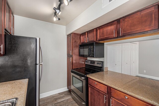 kitchen with dark hardwood / wood-style flooring, light stone counters, track lighting, electric stove, and fridge