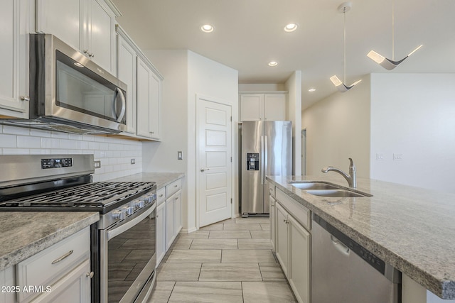 kitchen with white cabinetry, sink, light stone countertops, decorative backsplash, and appliances with stainless steel finishes