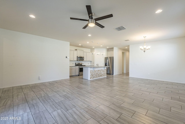 unfurnished living room featuring ceiling fan with notable chandelier