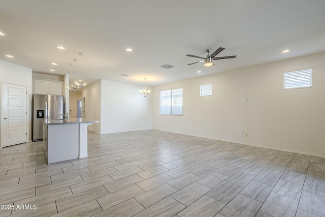 unfurnished room with ceiling fan with notable chandelier