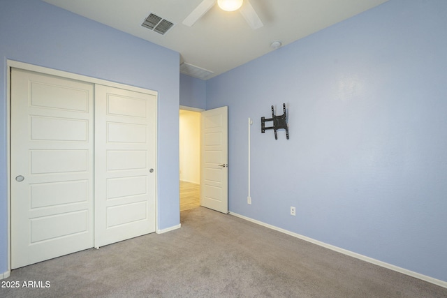 unfurnished bedroom with ceiling fan, light carpet, and a closet