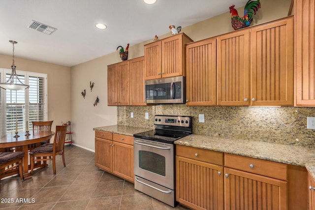 kitchen with light stone countertops, decorative light fixtures, stainless steel appliances, tasteful backsplash, and dark tile patterned flooring