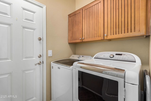 washroom with washer and dryer and cabinets