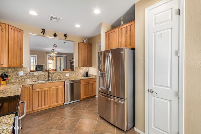 kitchen with stainless steel appliances, decorative backsplash, sink, and ceiling fan