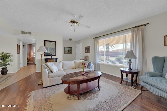 living room with ceiling fan, hardwood / wood-style flooring, and a textured ceiling