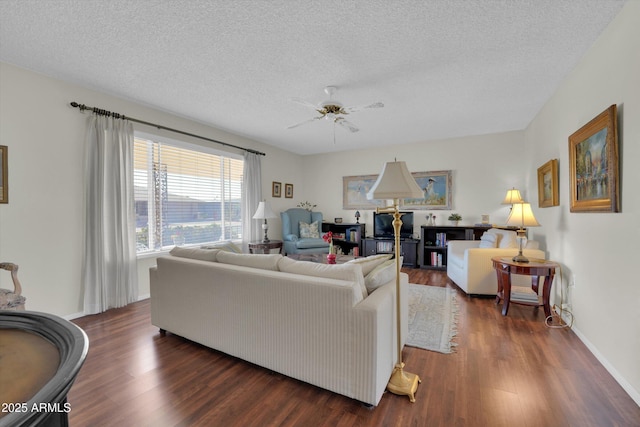 living room featuring ceiling fan, dark wood-type flooring, and a textured ceiling