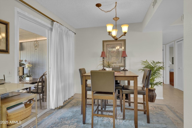 dining space featuring a textured ceiling and a chandelier