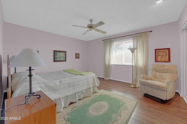 bedroom with a textured ceiling, light hardwood / wood-style flooring, and ceiling fan