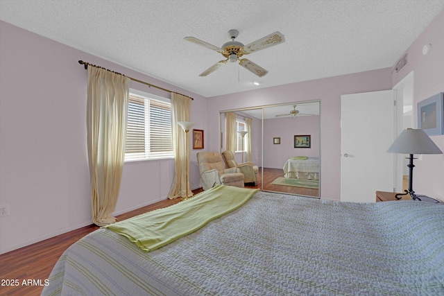 bedroom with hardwood / wood-style floors, a textured ceiling, ceiling fan, and a closet