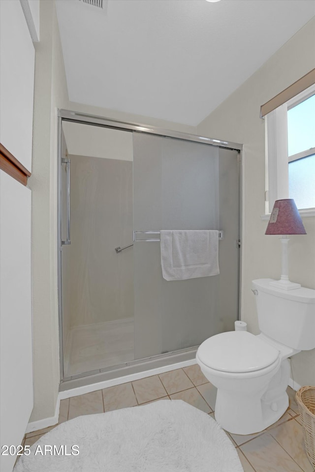 bathroom with tile patterned floors, toilet, and a shower with shower door