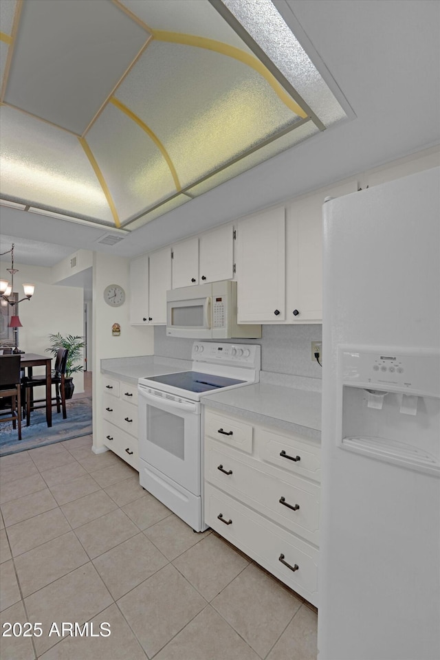 kitchen featuring light tile patterned floors, white appliances, and white cabinets