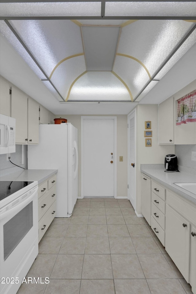 kitchen with white cabinetry, light tile patterned floors, and white appliances