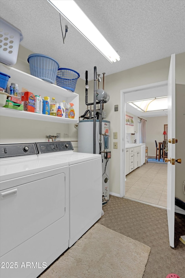 laundry area with water heater, light tile patterned floors, washer and dryer, and a textured ceiling