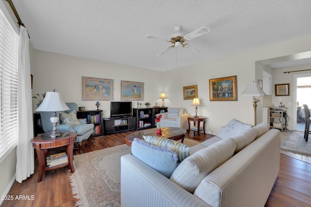 living room with dark hardwood / wood-style flooring, ceiling fan, and a textured ceiling