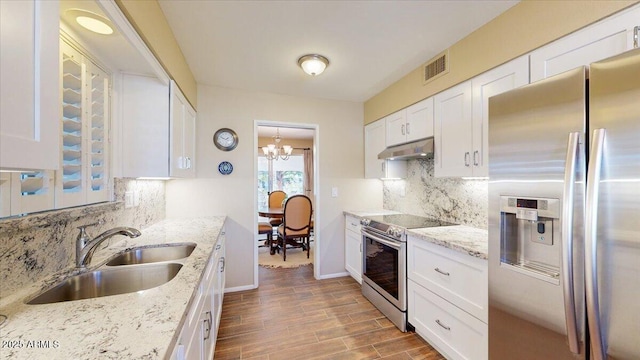 10506 W Desert Forest Cir, Sun City, AZ 85351 - kitchen with stainless steel appliances, a sink, under cabinet range hood, white cabinets, and backsplash