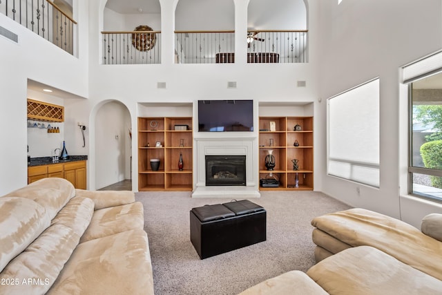 19242 W Pasadena Ave, Litchfield Park, AZ 85340 - carpeted living room with a ceiling fan, a towering ceiling, and a glass covered fireplace