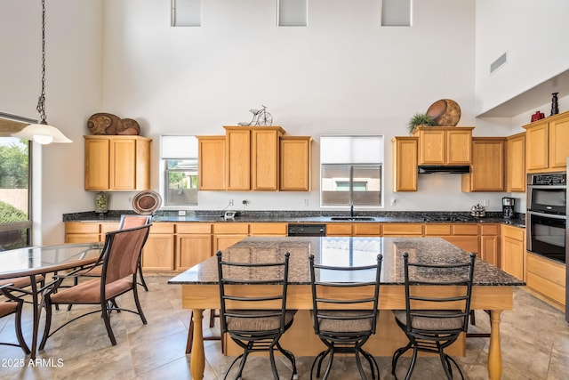 19242 W Pasadena Ave, Litchfield Park, AZ 85340 - kitchen with a towering ceiling, double oven, a sink, a breakfast bar area, and hanging light fixtures