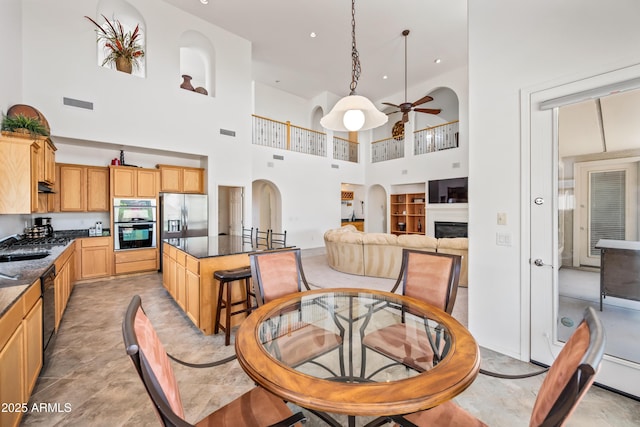 19242 W Pasadena Ave, Litchfield Park, AZ 85340 - dining room featuring a towering ceiling, a ceiling fan, a fireplace, arched walkways, and recessed lighting