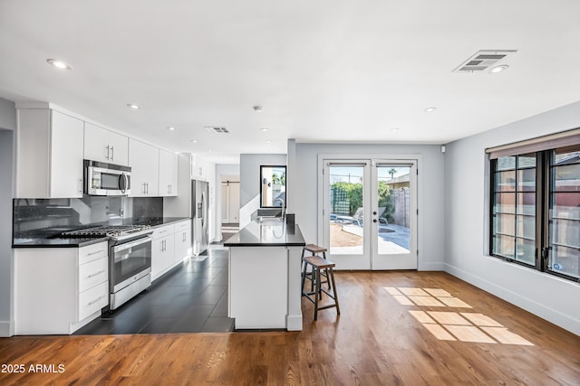 kitchen with stainless steel appliances, white cabinetry, sink, and a breakfast bar area