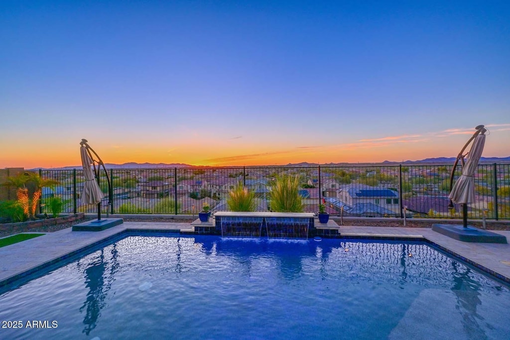 pool at dusk featuring pool water feature