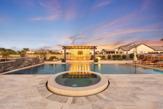 pool at dusk with an in ground hot tub and a patio area