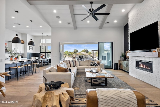 living room with beamed ceiling, light hardwood / wood-style flooring, a fireplace, and high vaulted ceiling