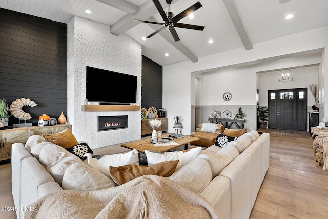 living room with light hardwood / wood-style flooring, lofted ceiling with beams, a fireplace, and ceiling fan