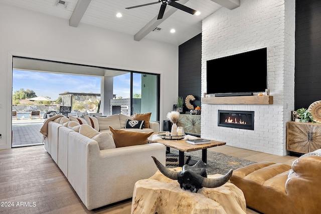 living room featuring beam ceiling, light hardwood / wood-style flooring, wood ceiling, and a fireplace