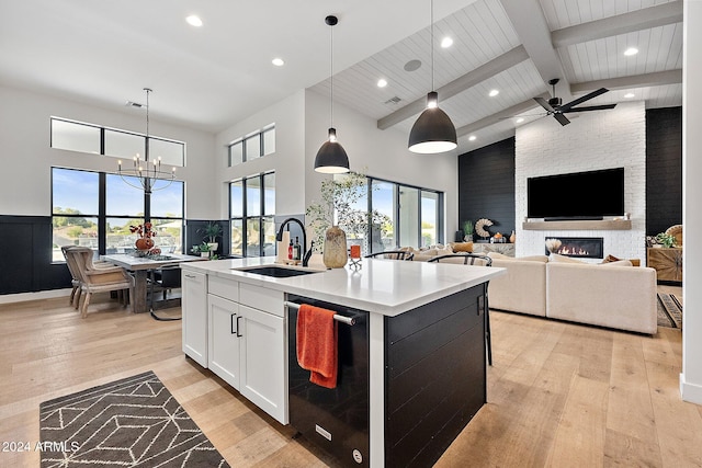 kitchen featuring a wealth of natural light, a kitchen island with sink, decorative light fixtures, and white cabinetry