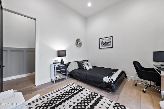 bedroom with light wood-type flooring and vaulted ceiling