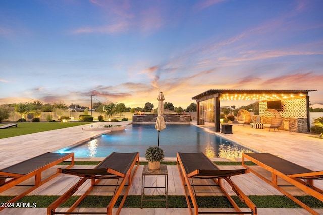 pool at dusk featuring a patio area