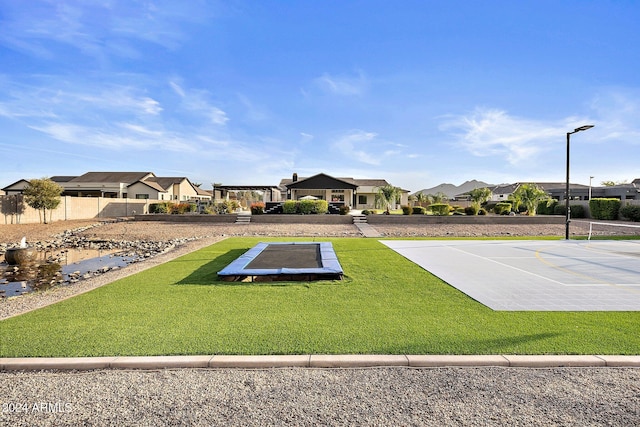 view of community with basketball court and a yard