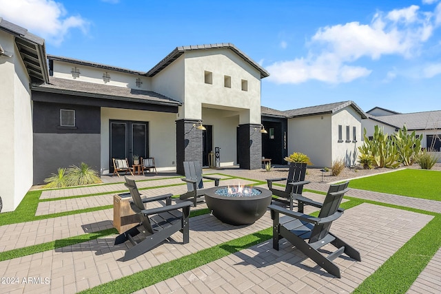 rear view of property with a patio and a fire pit