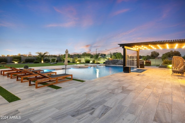 pool at dusk with a patio and pool water feature