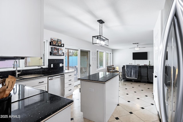 kitchen featuring white cabinets, hanging light fixtures, appliances with stainless steel finishes, a sink, and a center island