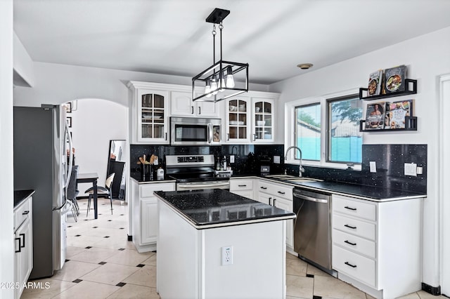 kitchen with white cabinets, a sink, stainless steel appliances, decorative backsplash, and glass insert cabinets