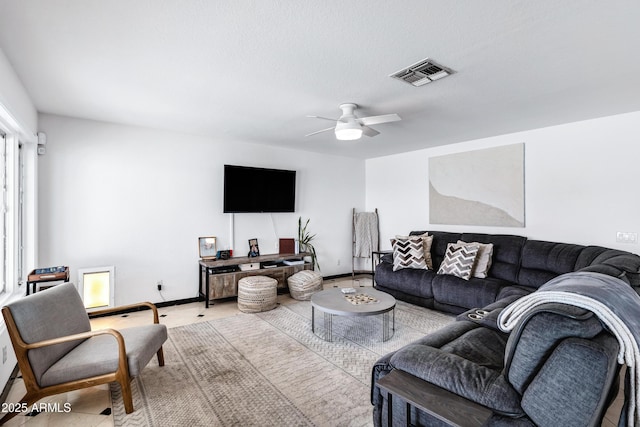 living area with baseboards, a ceiling fan, and visible vents