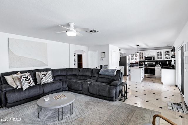 living room featuring visible vents, arched walkways, ceiling fan, and light tile patterned flooring