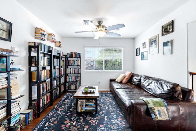 living area with baseboards, a ceiling fan, and wood finished floors