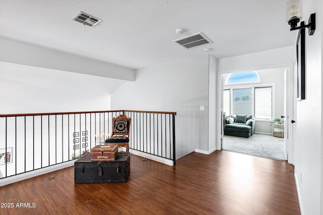 corridor featuring baseboards, visible vents, wood finished floors, and lofted ceiling