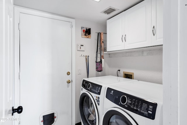 washroom featuring visible vents, cabinet space, and washer and dryer