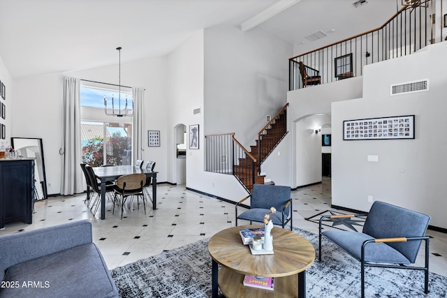 living area with arched walkways, stairs, a chandelier, and high vaulted ceiling
