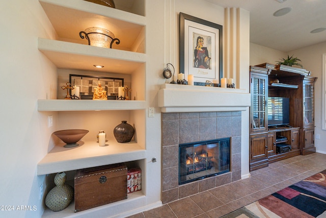 living room featuring built in shelves, tile patterned floors, and a tiled fireplace