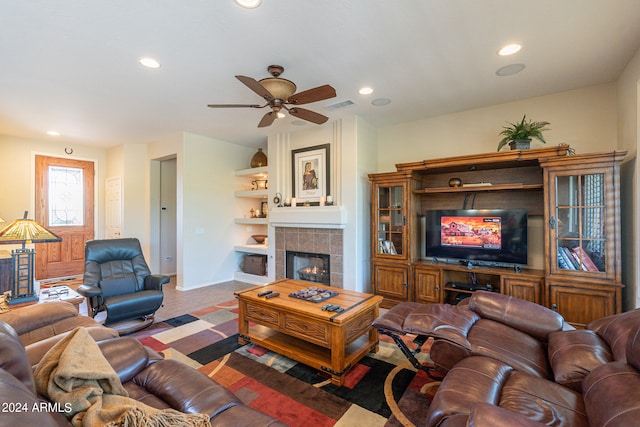 living room featuring ceiling fan, a tiled fireplace, and carpet flooring