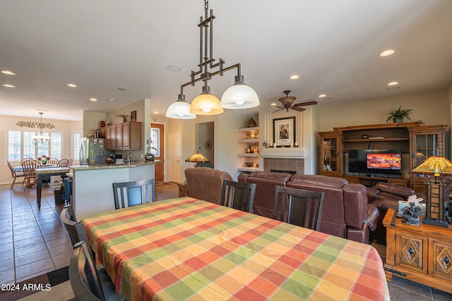 tiled dining area with ceiling fan and a fireplace