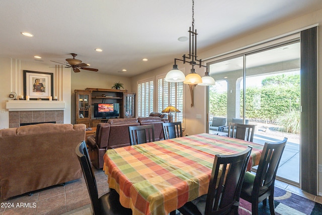 dining space featuring ceiling fan, a tiled fireplace, a wealth of natural light, and tile patterned flooring