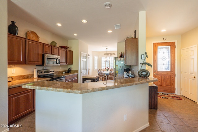 kitchen featuring light tile patterned floors, appliances with stainless steel finishes, kitchen peninsula, and a healthy amount of sunlight