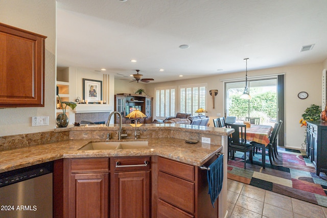 kitchen with ceiling fan, sink, dishwasher, a fireplace, and light stone countertops